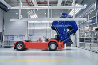 Blue and orange truck in workshop with cab tilted