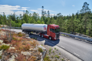 Red truck driving on road in forrest