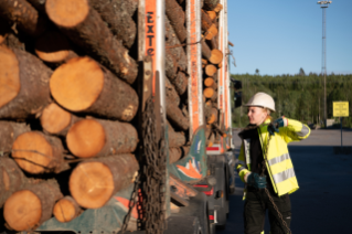Female driver standing next to truck with timber 