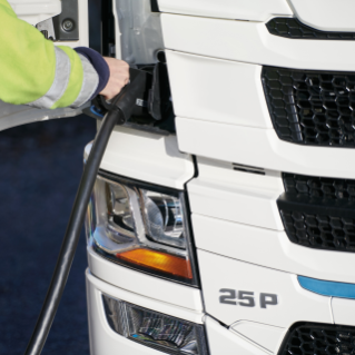 A person in safety jacket charging a white BEV truck