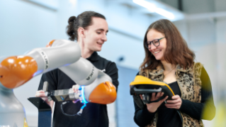 Two persons working with a robot