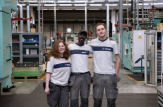 Three persons in workshop posing in front of camera