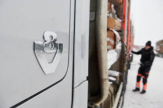 Close up shot of V8 badge on side of truck with driver checking the truck further away